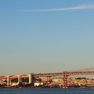 View of the 25 de Abril Bridge crossing the Tagus River in Lisbon at sunset.