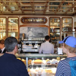 Clients and our guide Carlos inside a traditional Lisbon pastry shop with Portuguese pastries displayed at the counter.