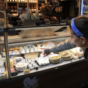 Client exploring a selection of traditional Portuguese cheeses at a local gourmet market.