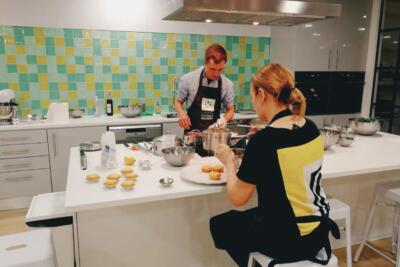 Participants in a traditional Portuguese cooking workshop, preparing and decorating pastéis de nata in a modern kitchen.