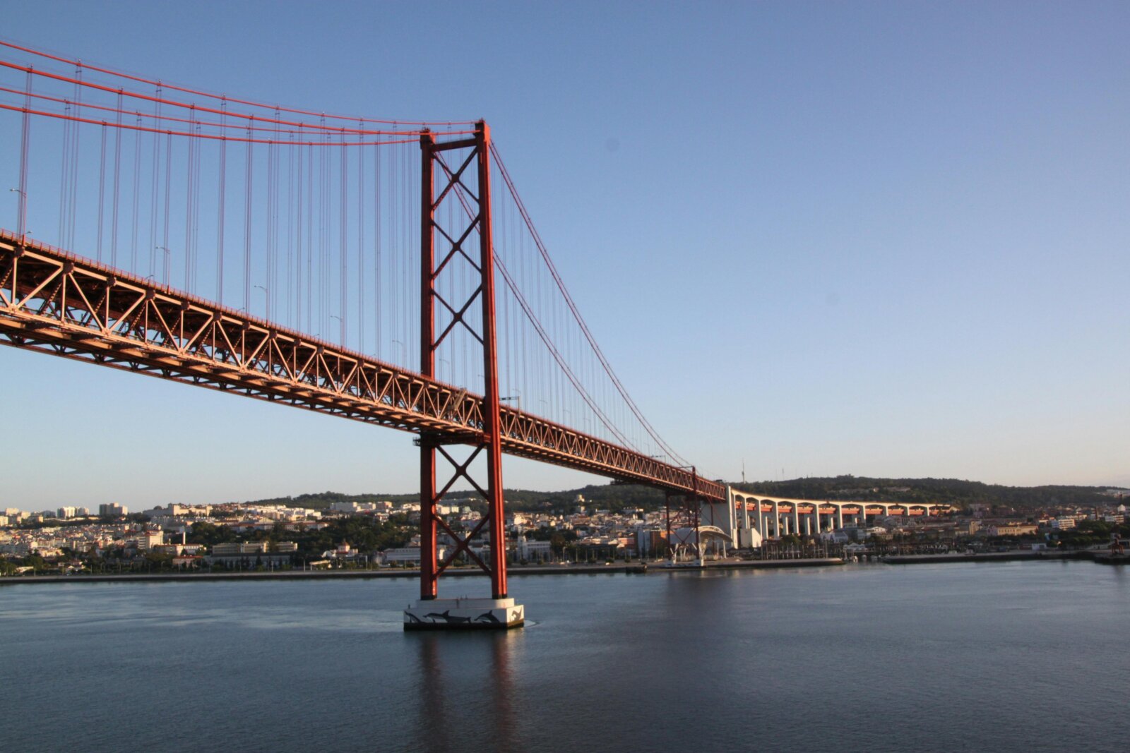 The 25th of April Bridge over the Tagus River in Lisbon, viewed at sunset, one of Portugal's most iconic architectural landmarks, is included in the panoramic tours of the city with Premium Tours.