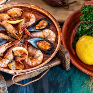 Traditional Portuguese seafood cataplana with prawns, mussels and clams served in a copper pan.