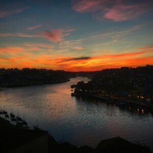 Sunset view over the Douro River with Porto and Vila Nova de Gaia silhouettes.