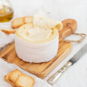 Creamy Serra da Estrela cheese served on a wooden board with bread.