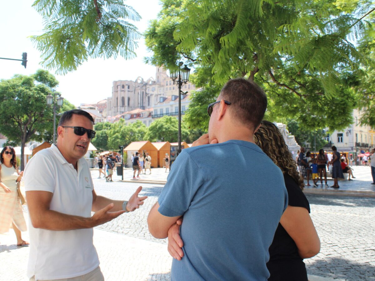 Herlander – Private Guided Tour in Lisbon | Portugal Premium Tours Private guide Herlander explaining Lisbon’s history to a couple in a historic square near Carmo Convent.