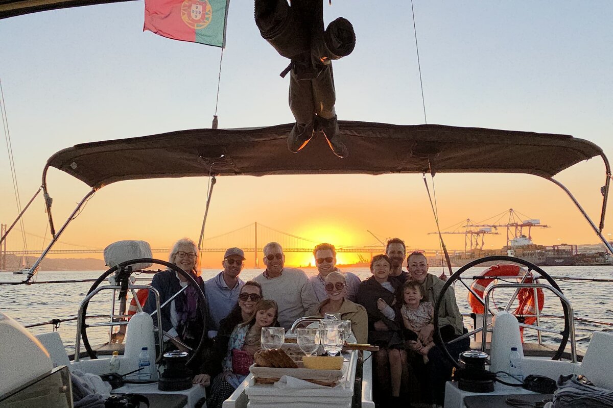 Clients enjoying a sunset sail on the Tagus River in Lisbon, with the 25 de Abril Bridge in the background.
