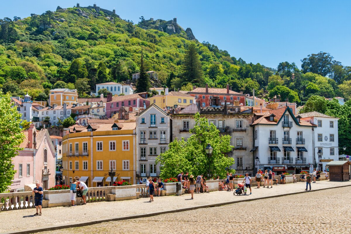 Panoramic view of Sintra's historic center with colorful buildings and the Castle of the Moors overlooking the hills.