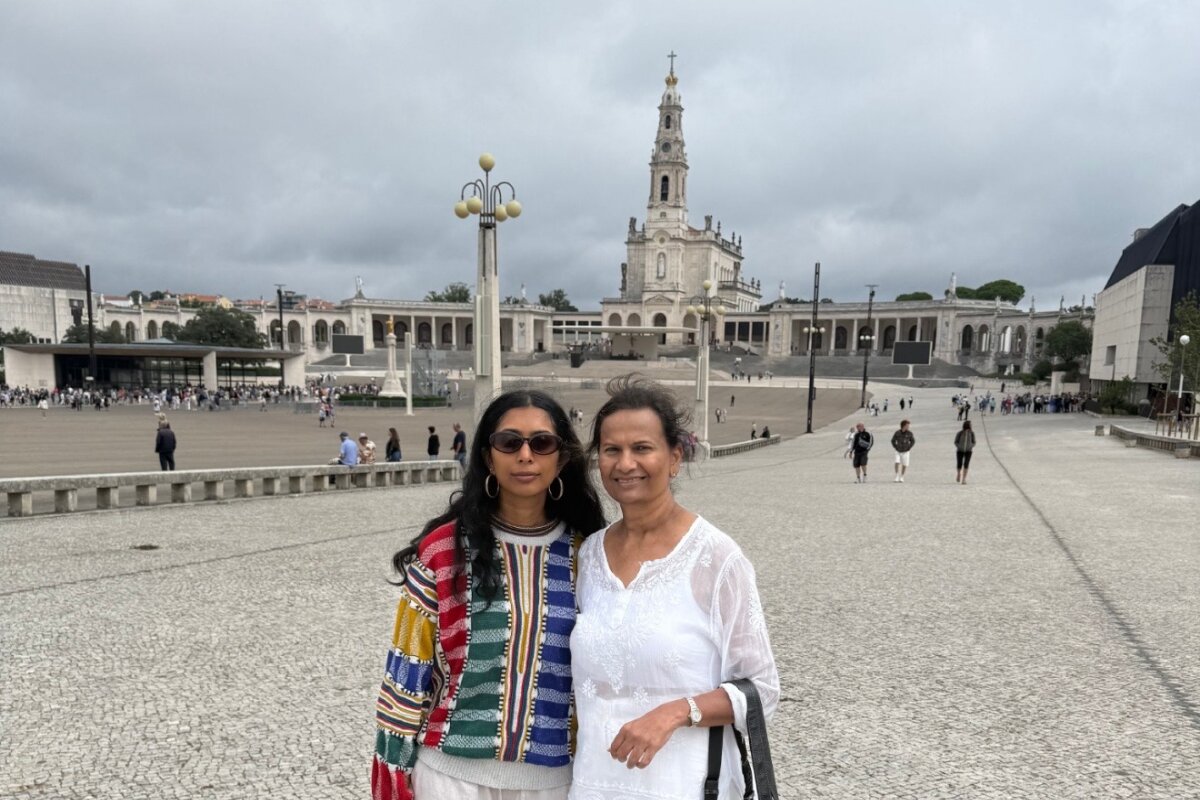 Two clients of Portugal Premium Tours smiling in front of the Basilica of Our Lady of the Rosary at the Sanctuary of Fátima, Portugal.